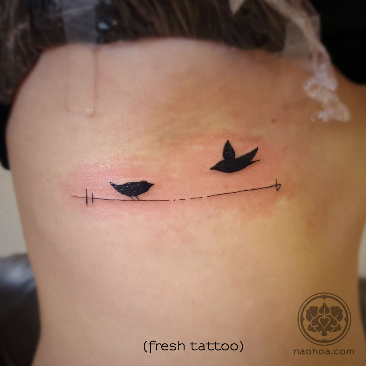 Two birds symbolising the client's children, along with their initials. Designed and tattooed by Naomi Hoang at NAOHOA Luxury Bespoke Tattoos, Cardiff (Wales, UK).