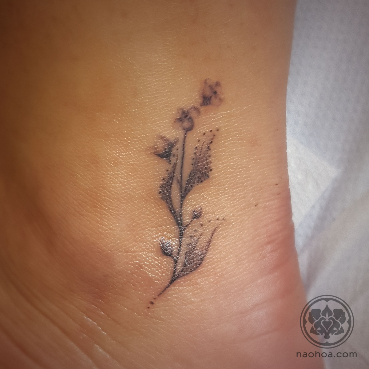 A delicate, feminine tattoo of forget-me-not flowers on a woman's ankle to symbolise each member of her family. Designed and tattooed by Naomi Hoang at NAOHOA Luxury Bespoke Tattoos, Cardiff (Wales, UK).
