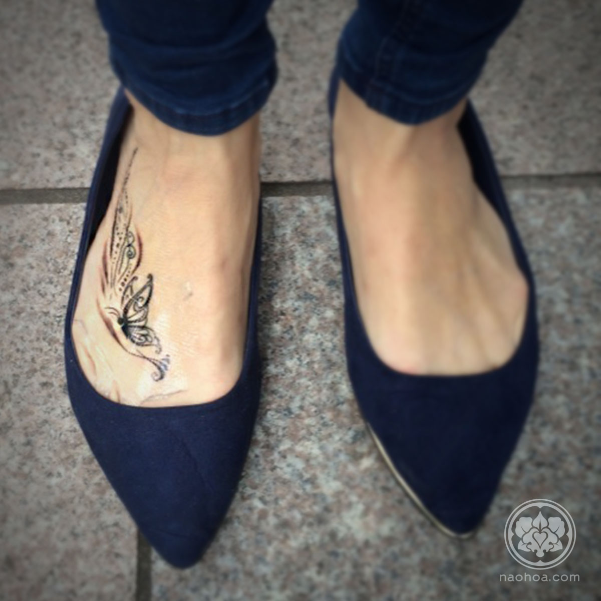 An un-healed tattoo of a butterfly and ornate decoration on the right foot.