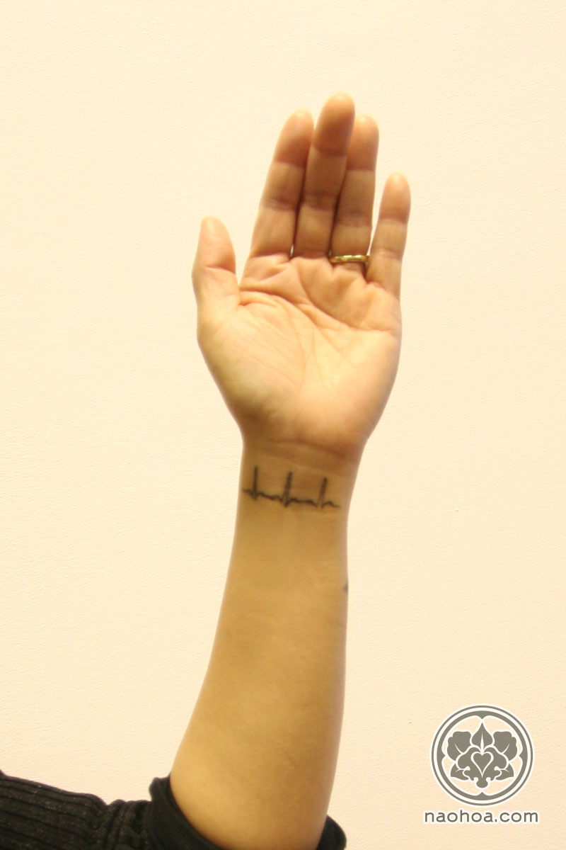 A small tattoo of an ECG scan on a woman's inner wrist.
