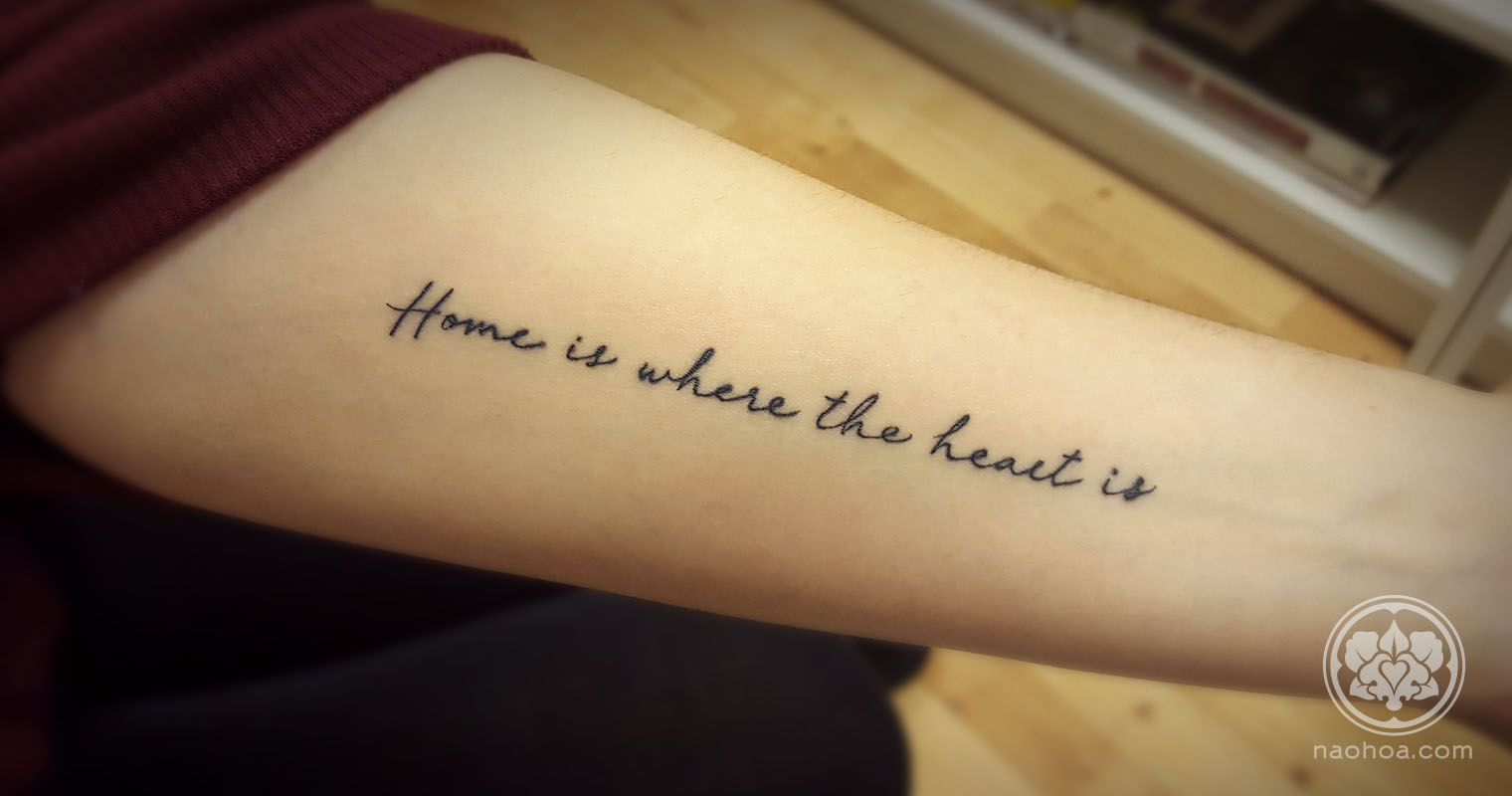 Tattoo of the quote, "Home is where the heart is" on a woman's inner arm. Designed and tattooed by Naomi Hoang at NAOHOA Luxury Bespoke Tattoos, Cardiff (Wales, UK).