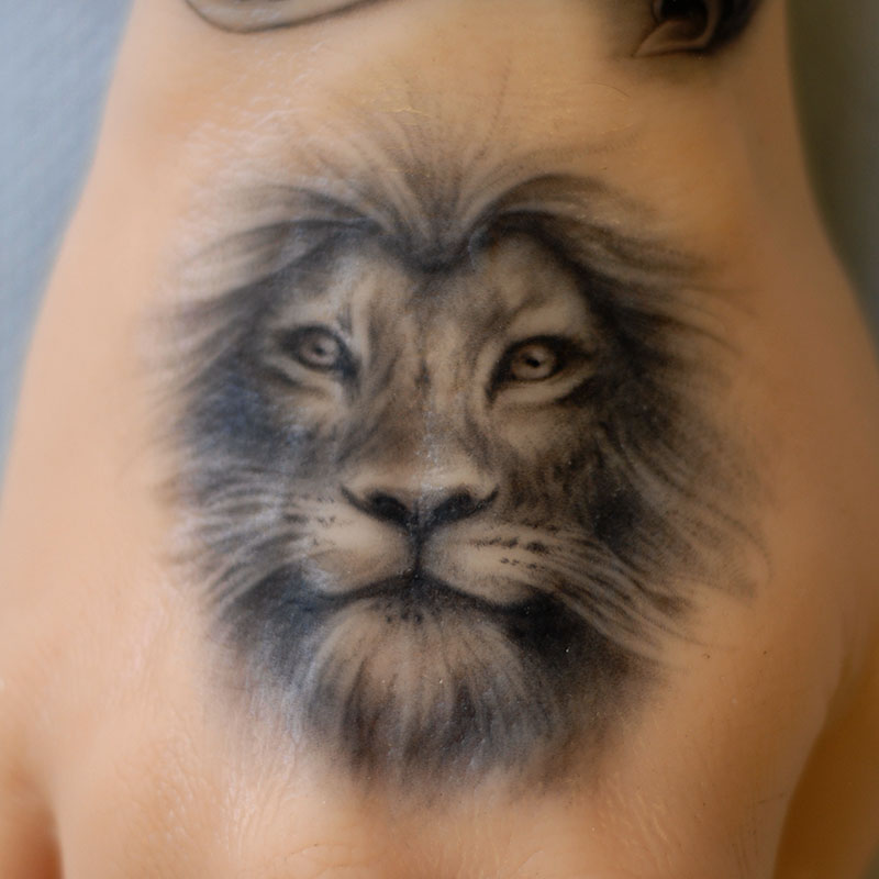 Realistic black and white lion tattoo on a Pound of Flesh arm by Naomi Hoang, NAOHOA Luxury Bespoke Tattoos, Cardiff, Wales (UK).