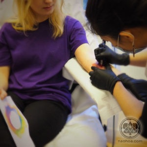 Photo of female tattoo artist Naomi Hoang at work in NAOHOA Luxury Bespoke Tattoos, Cardiff (Wales, UK).