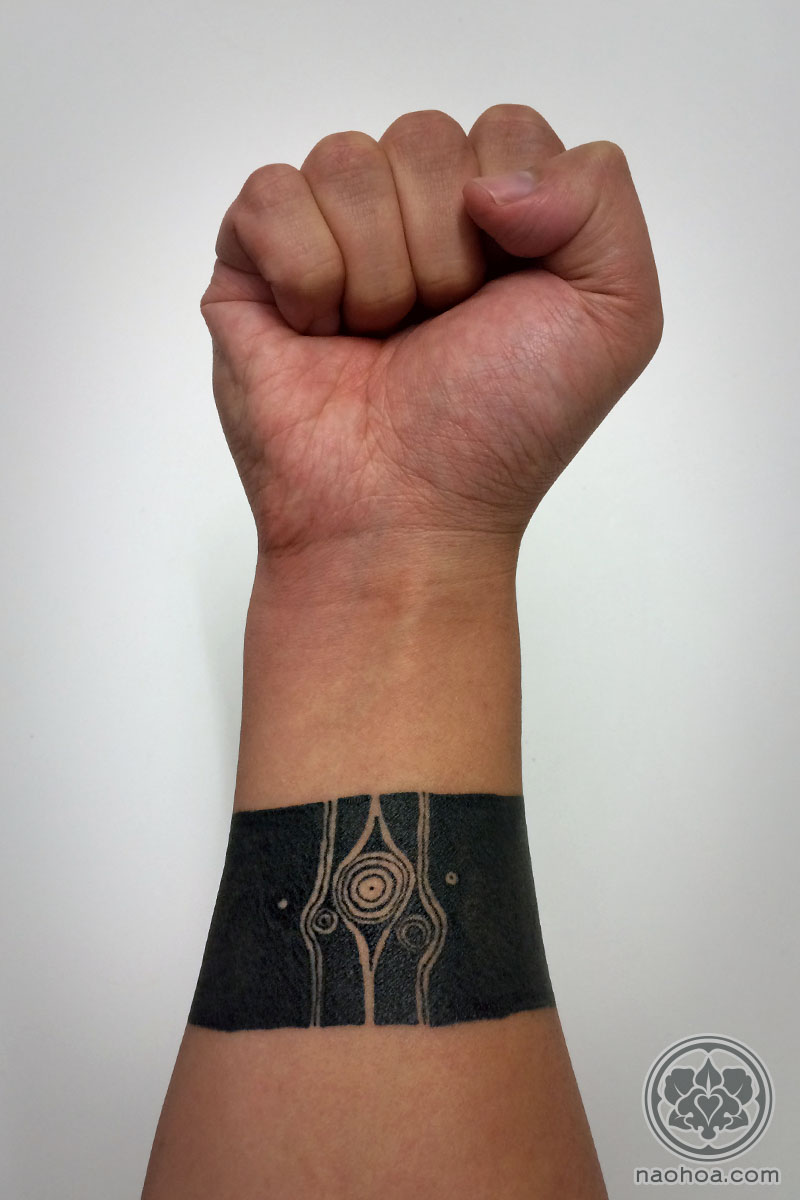 A solid black band around the wrist/forearm. Designed by Monument Valley artist Ken Wong and tattooed by Naomi Hoang, NAOHOA Luxury Bespoke Tattoos, Cardiff, Wales (UK).